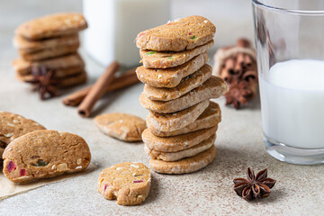 Danish spicy butter cookies with candied fruits, cinnamon sticks and anise and glass of milk, light concrete background.