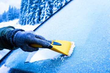 Clearing snow from windshield, Scraping ice. Winter season car window cleaning. Holiday in ski resort. - obrazy, fototapety, plakaty