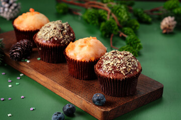Chocolate and orange cupcakes on a wooden board with Christmas decorations. Sweet muffins on the table