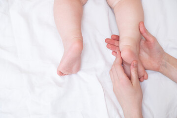 Baby feet on a female hand close up on white background. Mom and her child. Copy space