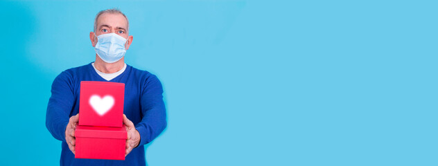 attractive man with protective mask on his face for coronavirus or covid-19 and present concept with gift boxes. Birthday or Valentine's Day