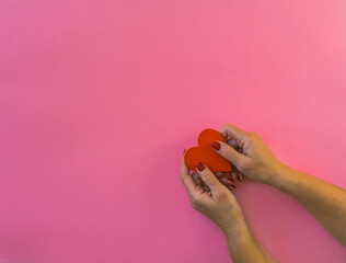 Woman hands holding red heart on pink background, copy space. Flat lay, top view. Valentine or love, spring holidays, Christmas and birthday concept.