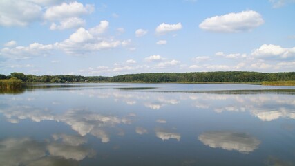 landscape with a Lackie lake in Poland and the clouds reflected in it against the blue sky