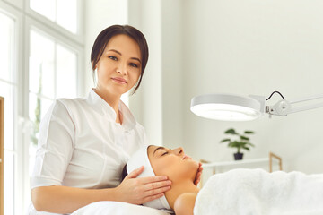 Woman dermatologist touching young womans face during checking skin or massage