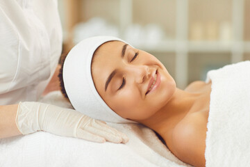 Smiling young womans face with clsed eyes expressing happiness during skincare procedure