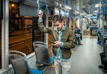 man with a phone rides in a night tram