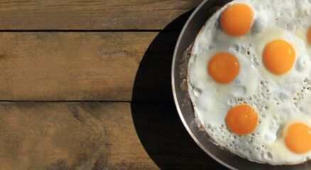 cast iron skillet with many fried chicken eggs on a wooden table top view. a large dish with a...