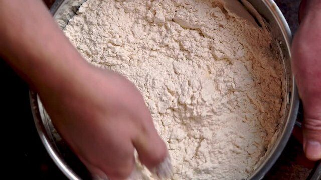 Italian Pizza Dough. chef mixes the ingredients for the dough with his hand DIY homemade dought concept.