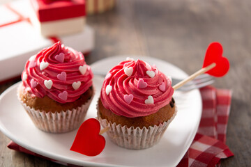 Cupcake decorated with sugar hearts and a cupid arrow for Valentine's Day on wooden table