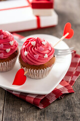 Cupcake decorated with sugar hearts and a cupid arrow for Valentine's Day on wooden table