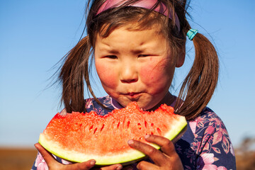 The extreme north, Yamal, life of Nenets people, the dwelling of the peoples of the north, a girl eats watermelon for the first time, little girl is eating a big watermelon