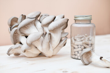 a bottle of mushroom supplement capsules and fresh mushrooms on a wooden table. antioxidant and...
