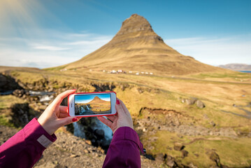 Woman takes pictures of the mountain on a smartphone in Iceland