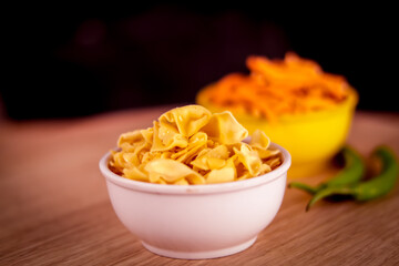 Papdi gadhiya is Indian Namkeen and popular tea time snack in Gujarat and Kutch,Papdi Gathiya in white bowl with onion and chili peppers on tabl