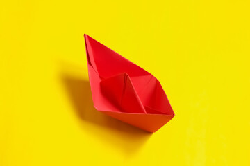 Red paper ship isolated on yellow background. Origami boat.