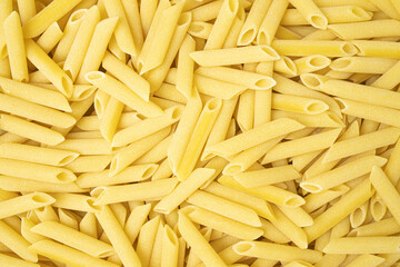 Uncooked or dry penne lisce type of pasta texture background.