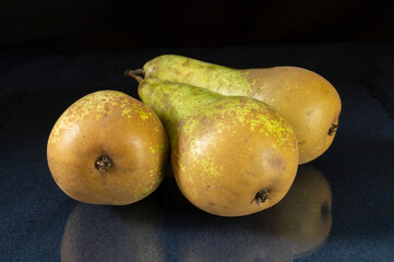 Ripe pear rests upon turn blue table with reflection