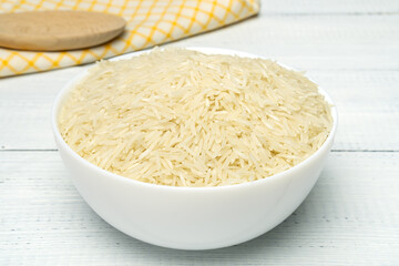 White long basmati rice in white ceramic bowl on wooden table. Gluten free food.