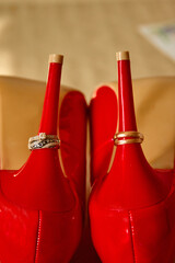Wedding shoes and ring. Close-up. Red shoes. Gold wedding rings on heel of shoe.