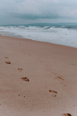 footprints in the sand. beach, wave and footprints on a sandy beach. Sea, sand. cloudy sky.