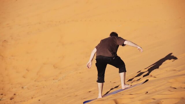 Tourist On Board Surfing Down Sand Dune