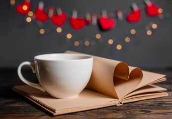 Heart made from book sheets with a cup in lights, love and valentine concept on a wooden table
