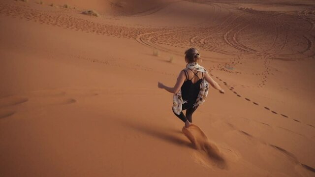 Tourist Running Barefoot Down Desert Sand Dune