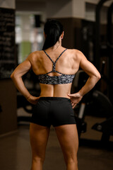 back view of healthy strong woman in sportswear standing in gym