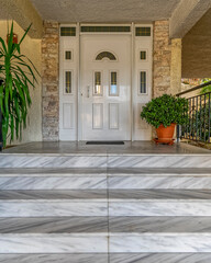 Fototapeta premium marble steps to house entrance white door and flowerpot