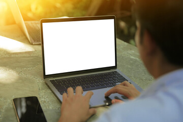 Cropped image of a young man working on his laptop in a garden, rear view of business man hands busy using laptop at office desk, typing on computer sitting at wooden table
