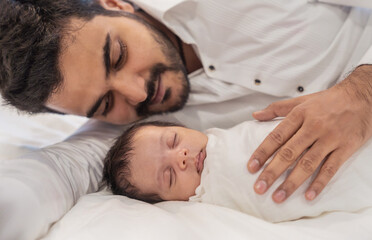 Obraz na płótnie Canvas Portrait of young happy asian Indian father with his newborn baby, copy space with bed in the hospital background. Family love together father’s day holiday concept