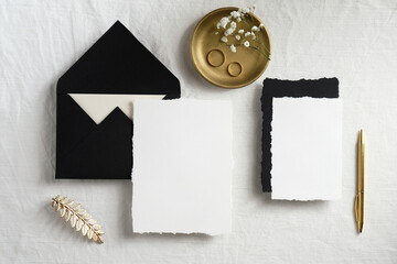 Handmade paper invitation cards or wedding stationery mockup with card and envelope on bed. Minimal style. Flat lay, top view.