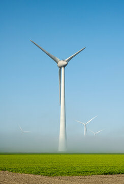 Offshore wind turbines standing in fog on the IJsselmeer inland sea, land based turbines in the clear, Flevoland, Netherlands
