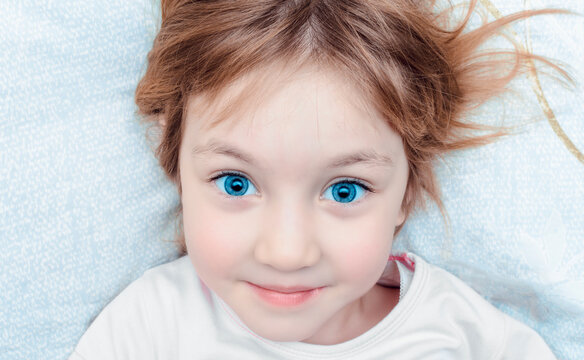Cheerful child with smile on his face lies on pillow before bed.
