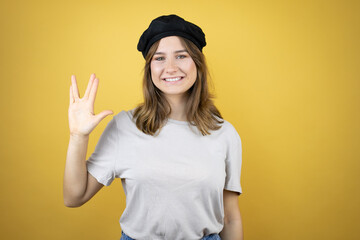 Beautiful young caucasian girl wearing french look with beret over isolated yellow background doing star trek freak symbol