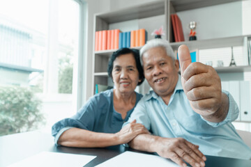 Senior Asian couple using the calculator and paperwork on desk at home to calculate expenses and income. And savings after retirement. Concept of financial planning and investment for retirees.