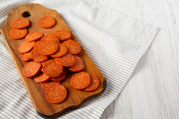 Italian Pepperoni Slices on a rustic wooden board on cloth, low angle view. Copy space.