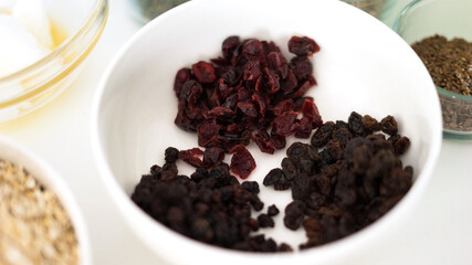 bowl of cranberries and sultanas with granola ingredients around