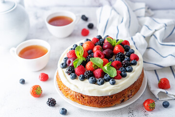 Cake with cream cheese frosting, mint leaves and strawberries, blueberries; blackberries and raspberries