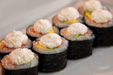 Sushi rolls with fish, caviar, creamy sauce, avocado, on a white plate