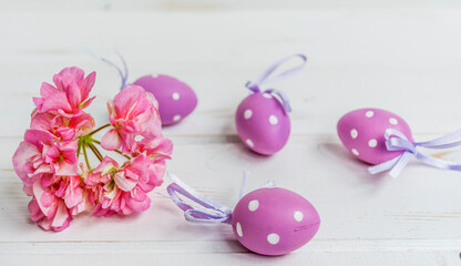 Purple Easter Eggs with White Dots and Pink Flowers on a White  Wooden Background 
