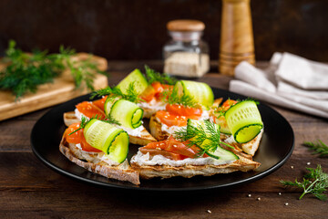Toasts with salted salmon fish, ricotta cheese, fresh cucumber and ciabatta bread
