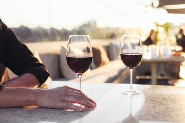 Two glasses of red wine on a restaurant luxury terrace, sunset light