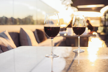 Two glasses of red wine on a restaurant luxury terrace, sunset light