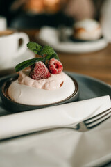 Pavlova cake with frozen raspberries and a sprig of mint