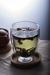 A green tea in a double glass cup on a linen cloth against white background