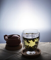 A green tea in a double glass cup on a linen cloth against white background