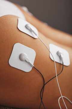 Myostimulation electrodes on the buttocks and legs of a woman in a beauty salon.