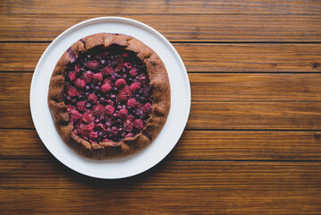 Delicious freshly baked vegan almond berry galette on wooden rustic background, top view. Copy space. Sweet food, summer dessert.
