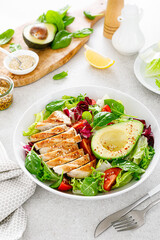 Fototapeta na wymiar Grilled chicken meat and fresh vegetable salad of tomato, avocado, lettuce and spinach. Healthy and detox food concept. Ketogenic diet. Buddha bowl dish on white background